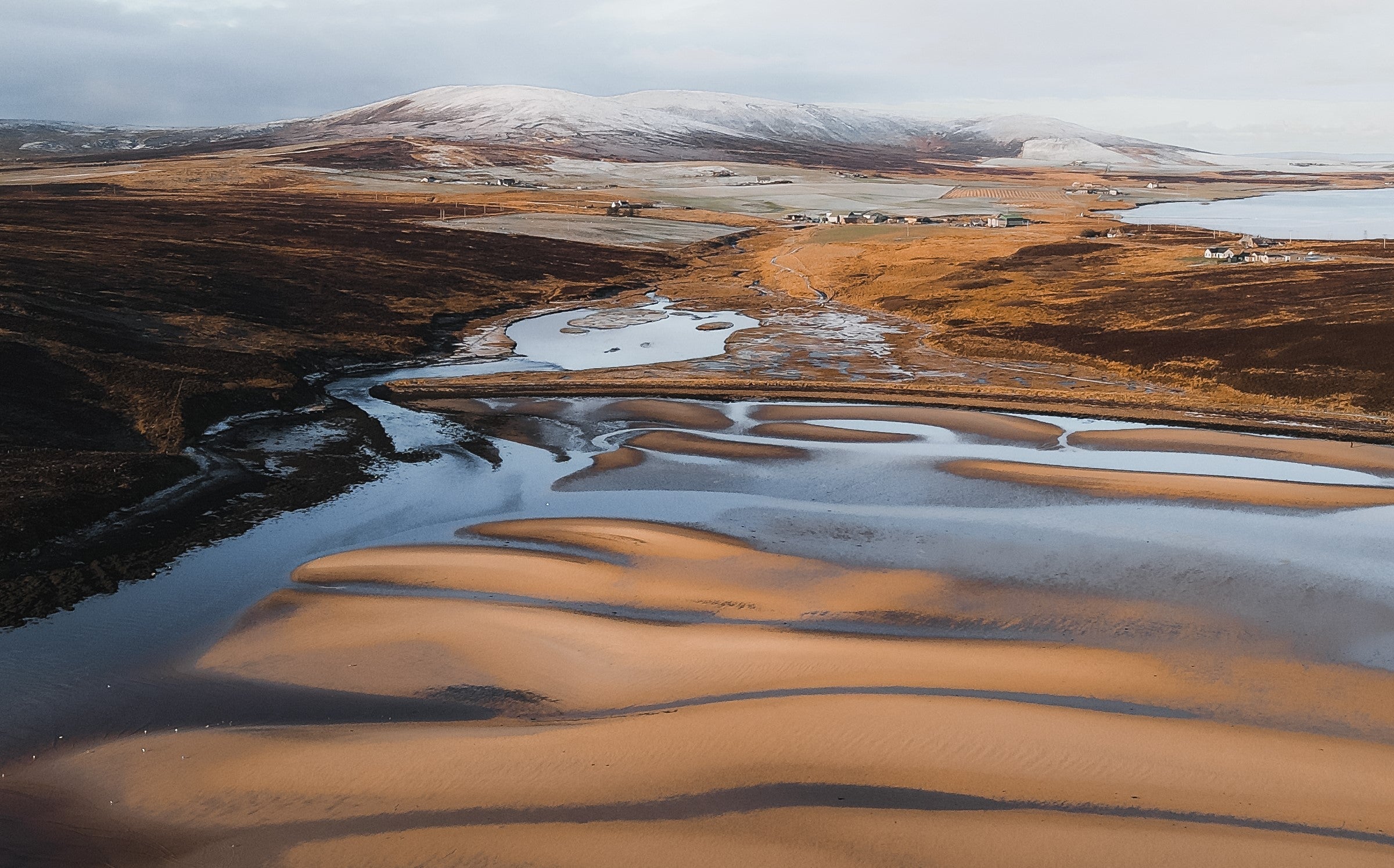beach at low tide with snow on hills in background