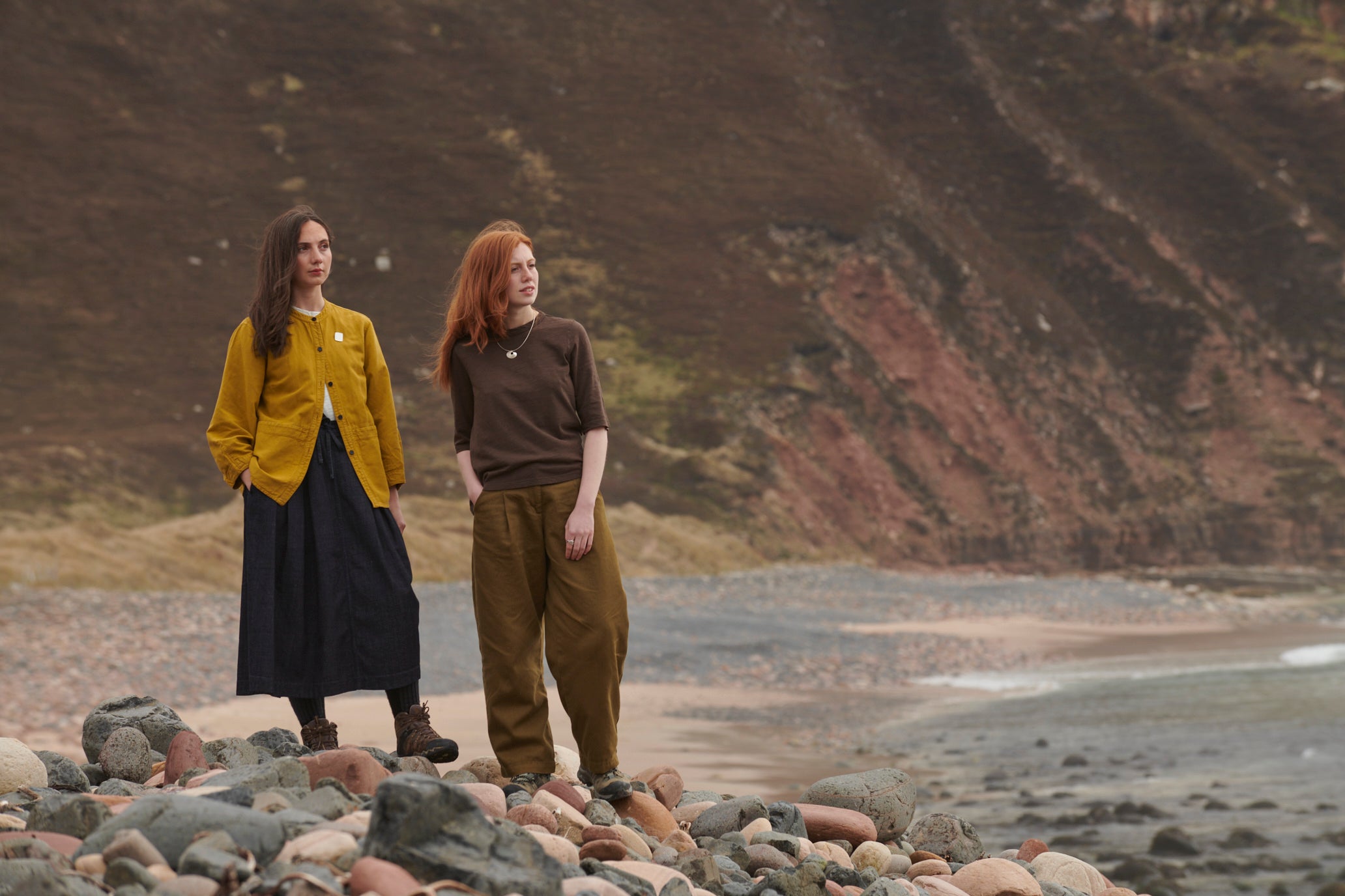 Two women standing on the beach at Rackwick, looking out to sea wearing silver necklaces