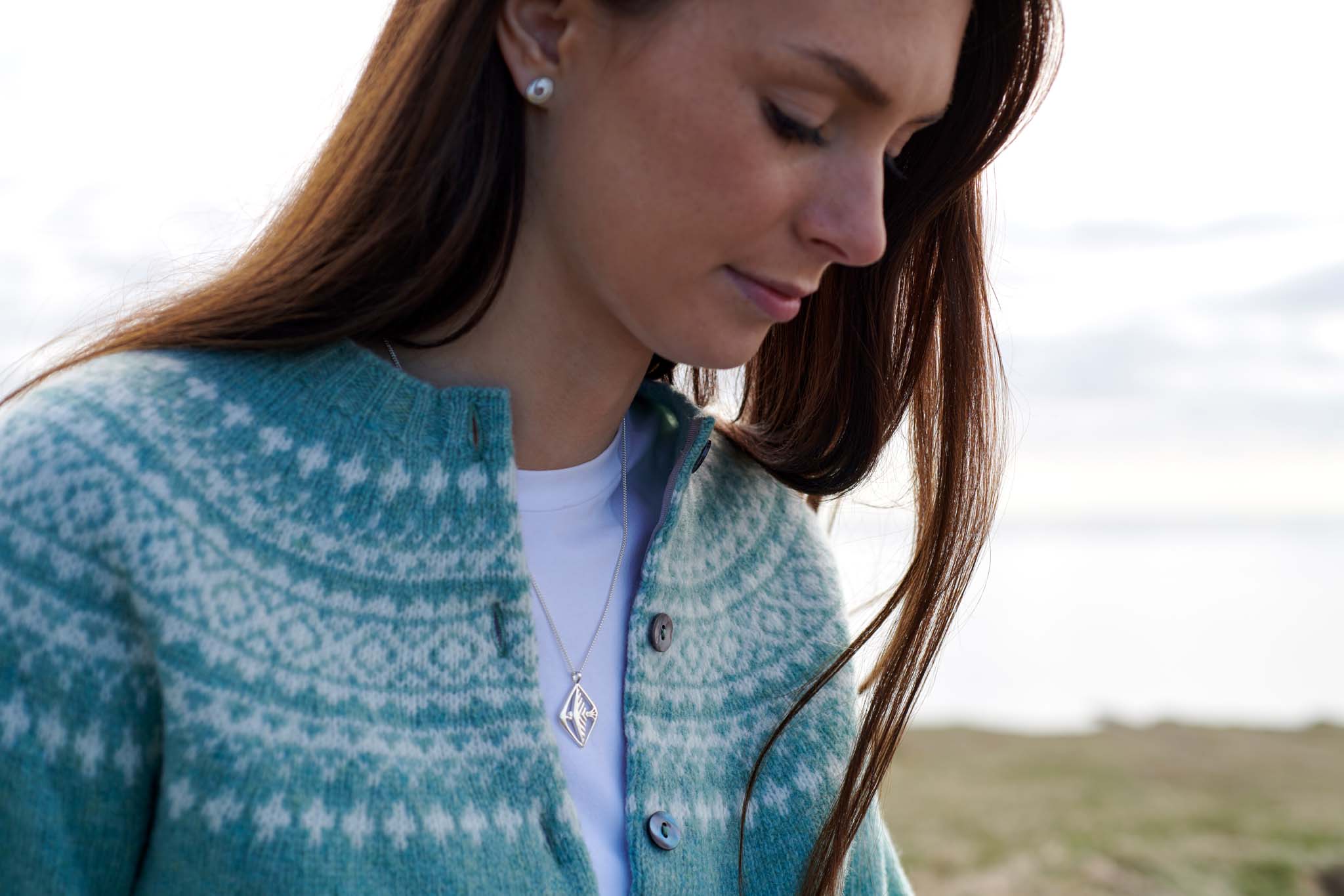 woman wearing teal knitwear and silver necklace