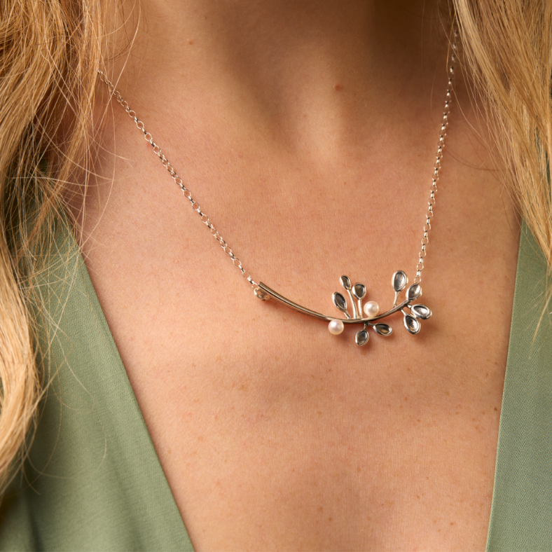 Necklace with leaf design worn by a person