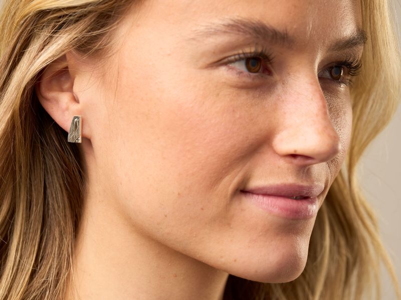 Close-up of a woman's face with blonde hair and earrings.