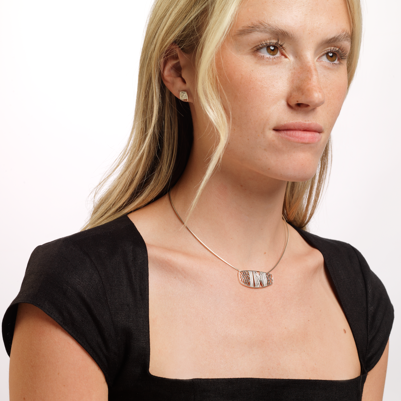 Woman in black top wearing ness of brodgar necklace and stud earring