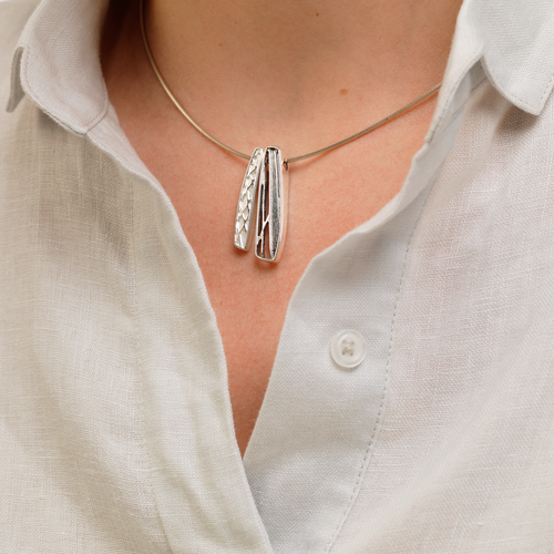 Model wearing Ola Gorie silver Ness of Brodgar pendant, inspired by Neolithic art