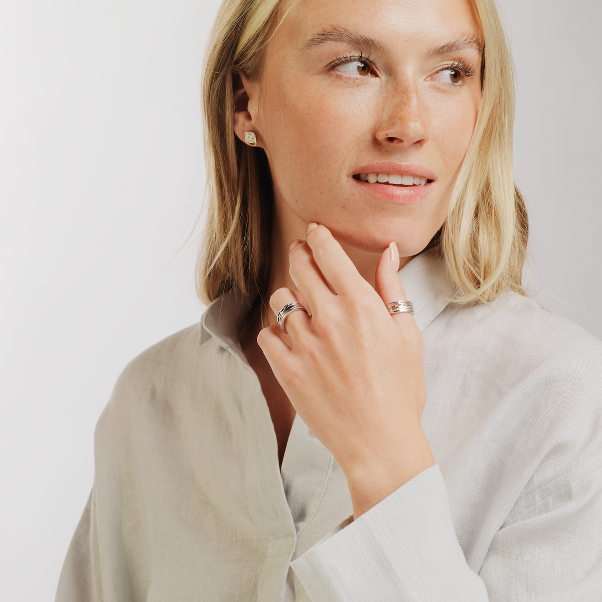 woman in a white shirt wearing two rings and square studded earring