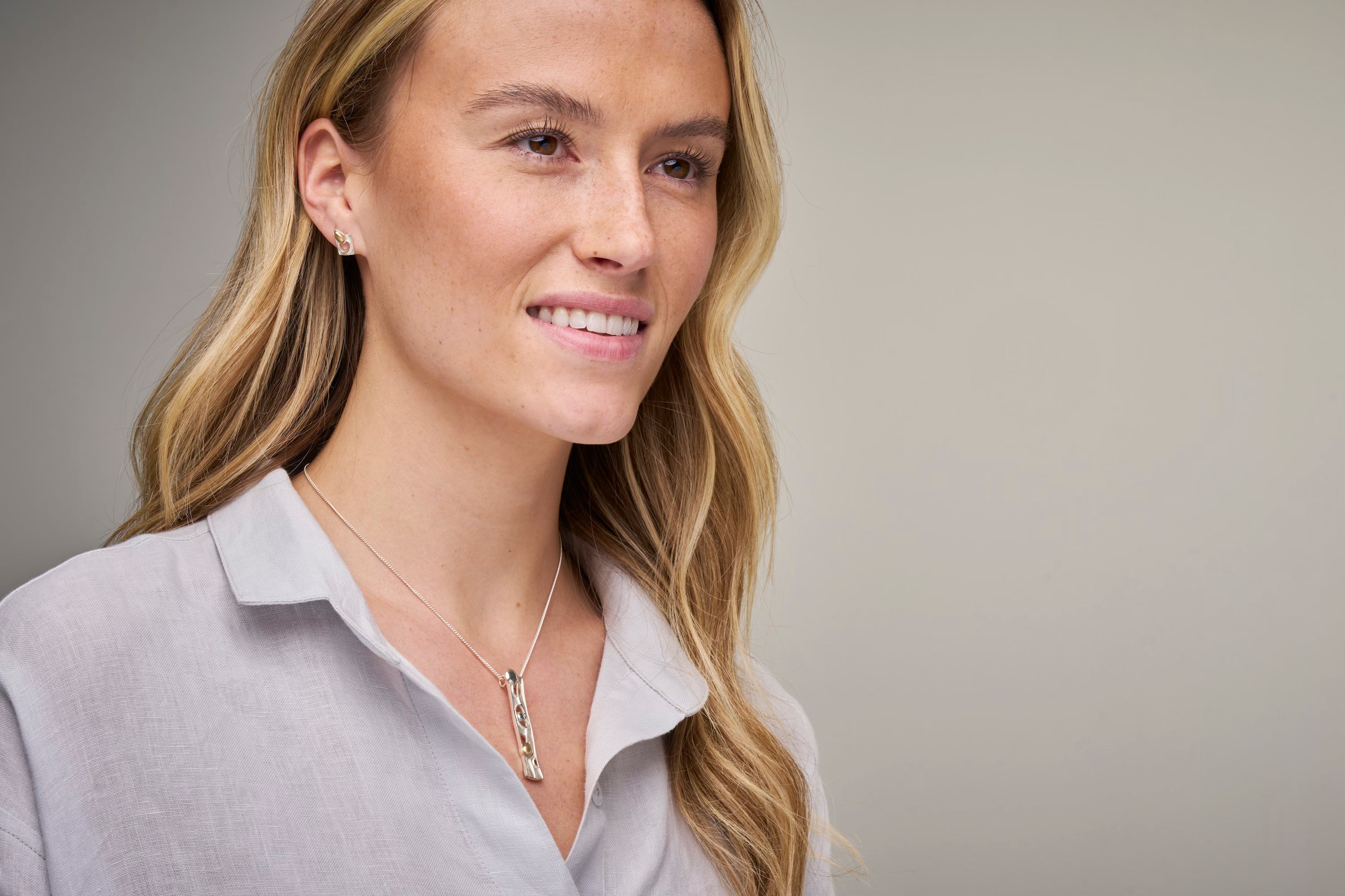 woman in grey top with necklace and earrings