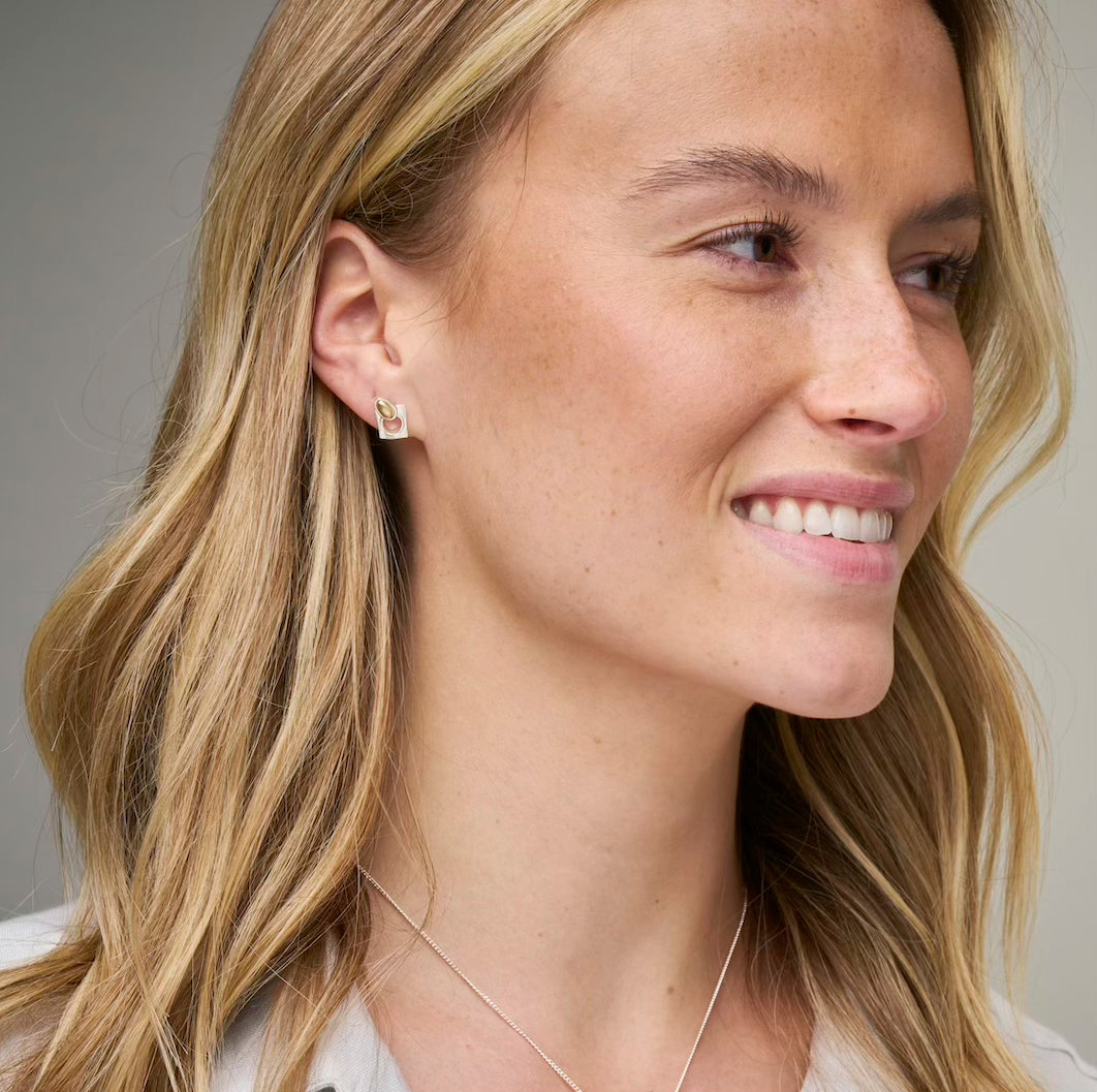 woman in grey top with stud earring