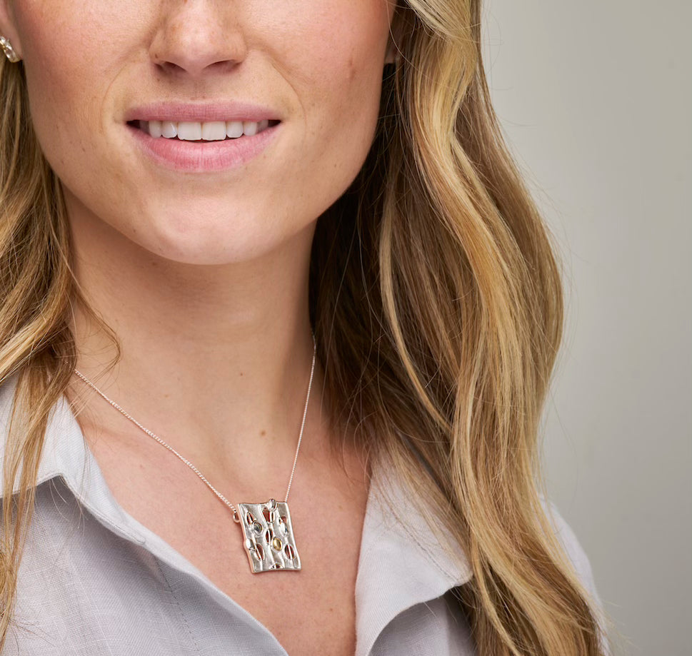 Woman in grey top with square necklace close up