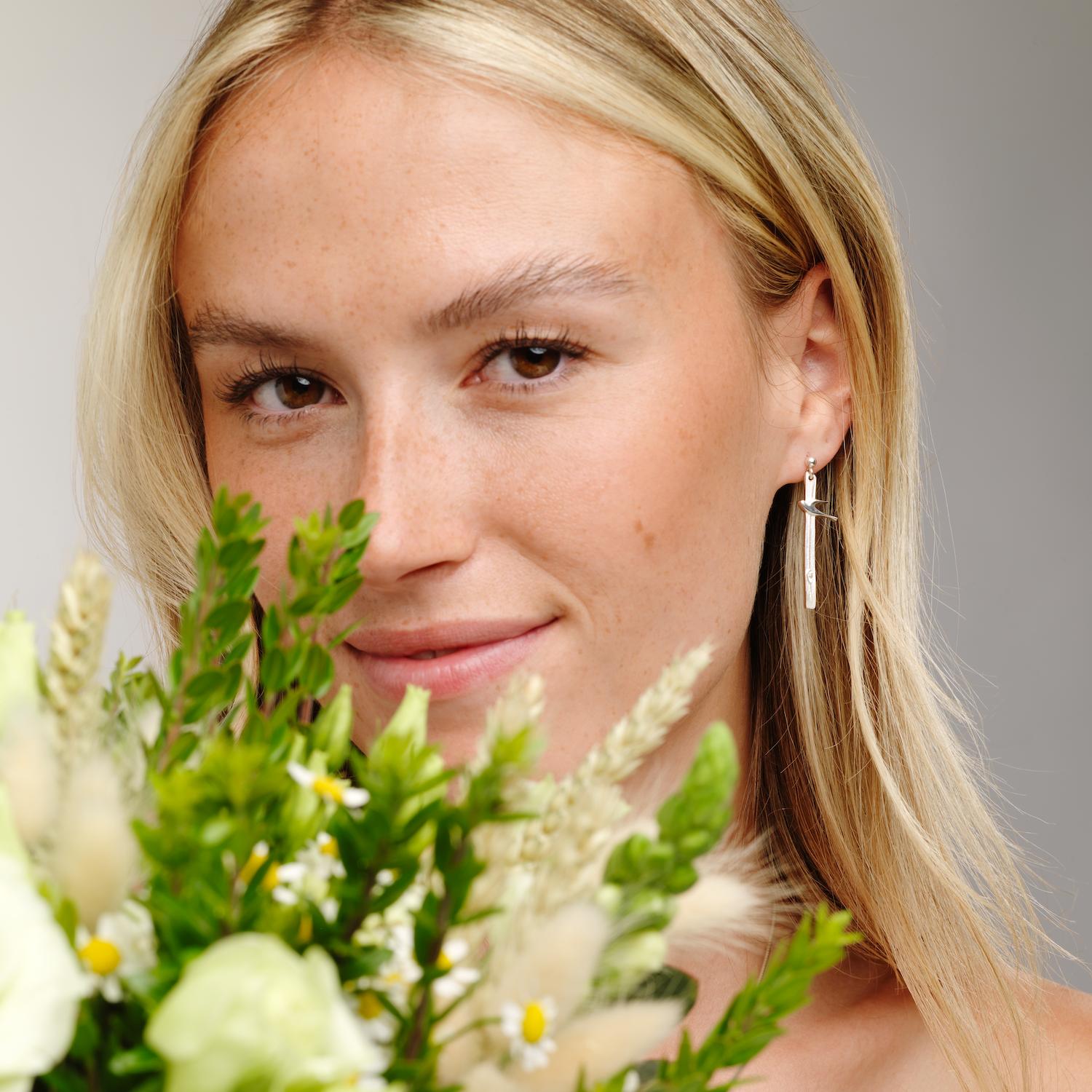 Woman with flowers wearing birdland drop earring