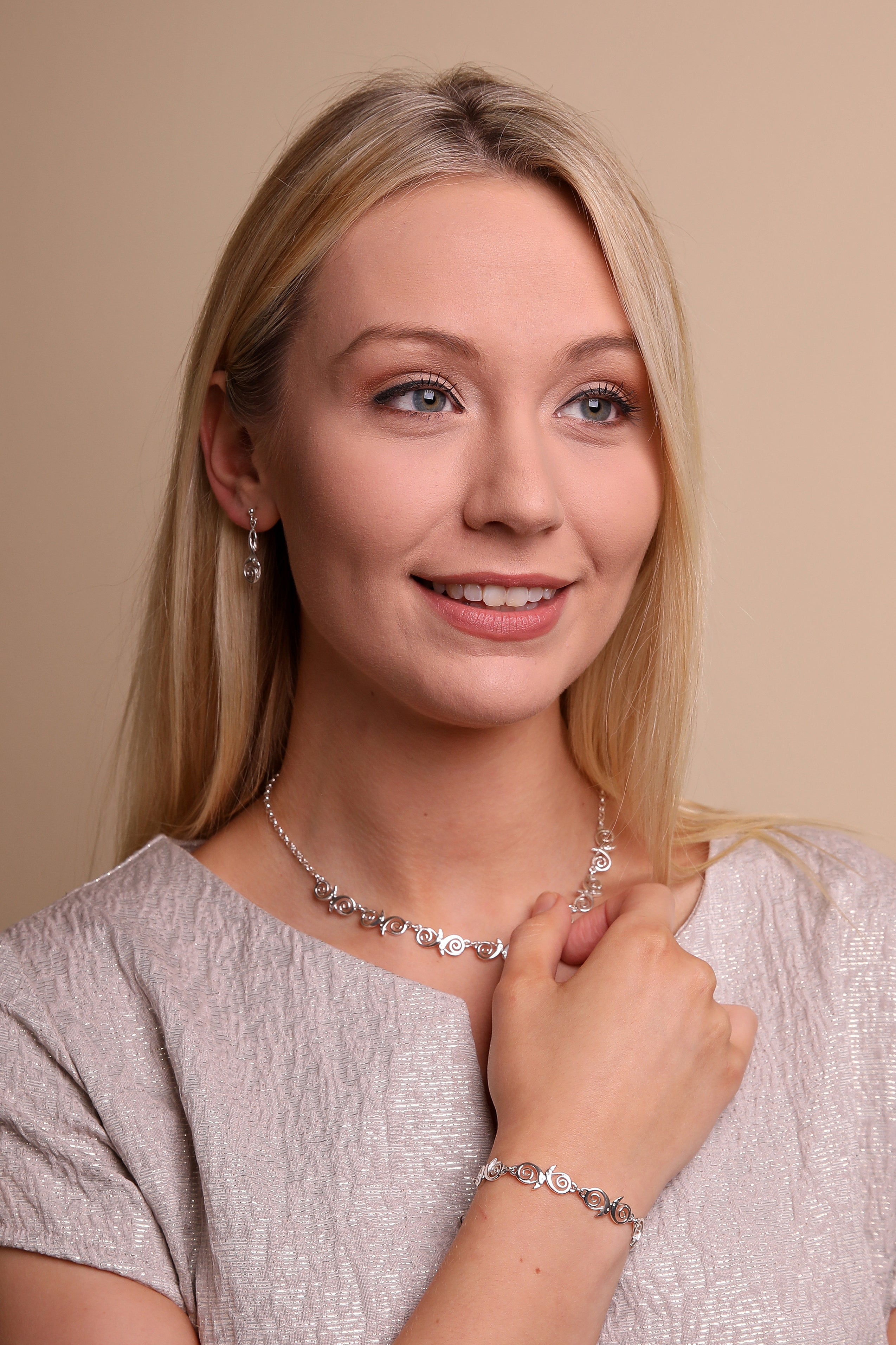 Woman in silver top models silver earring, necklace and bracelet from the Kells Bird Collection