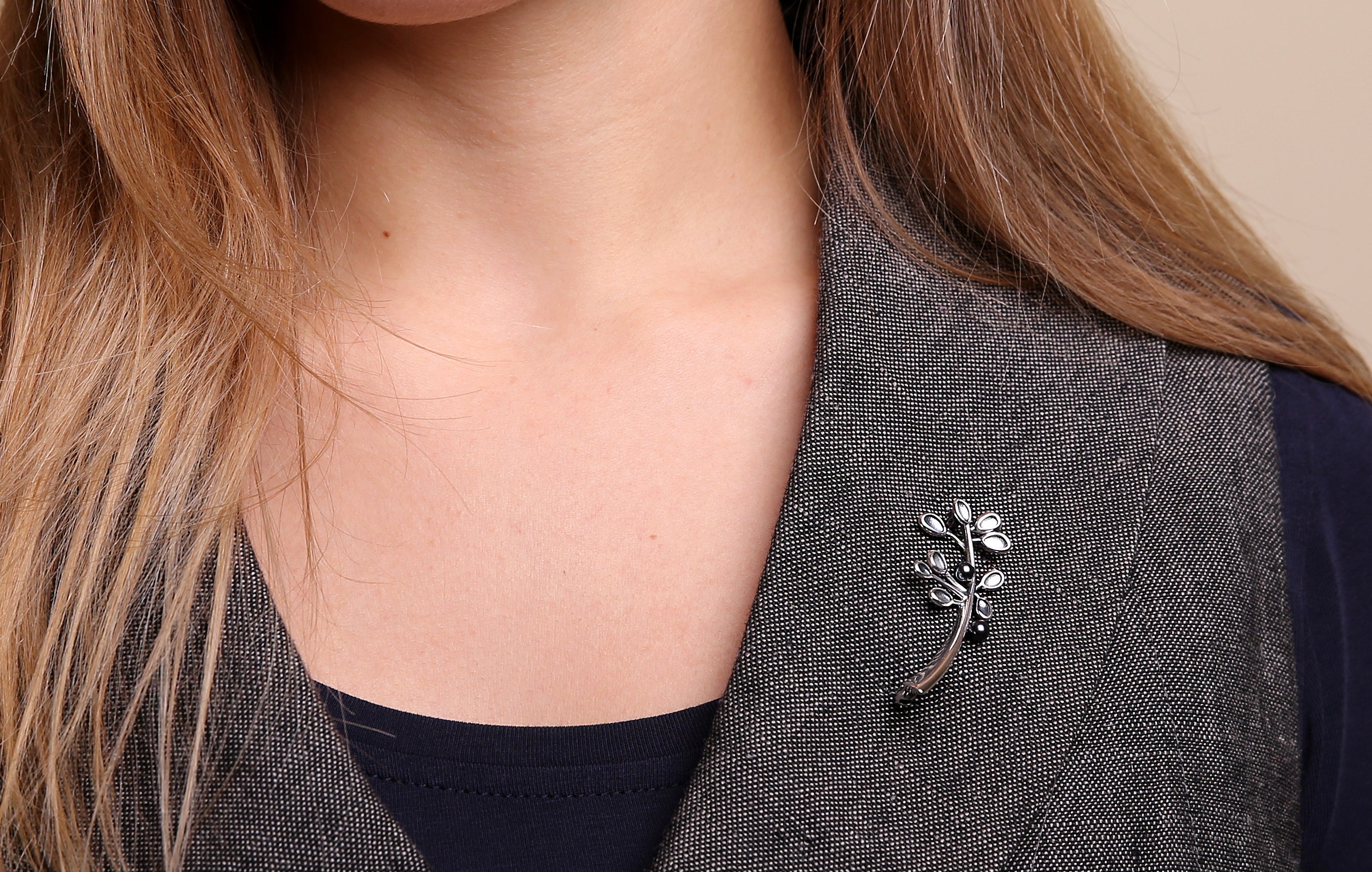 Woman in grey waistcoat is modelling a silver Cloudberry brooch