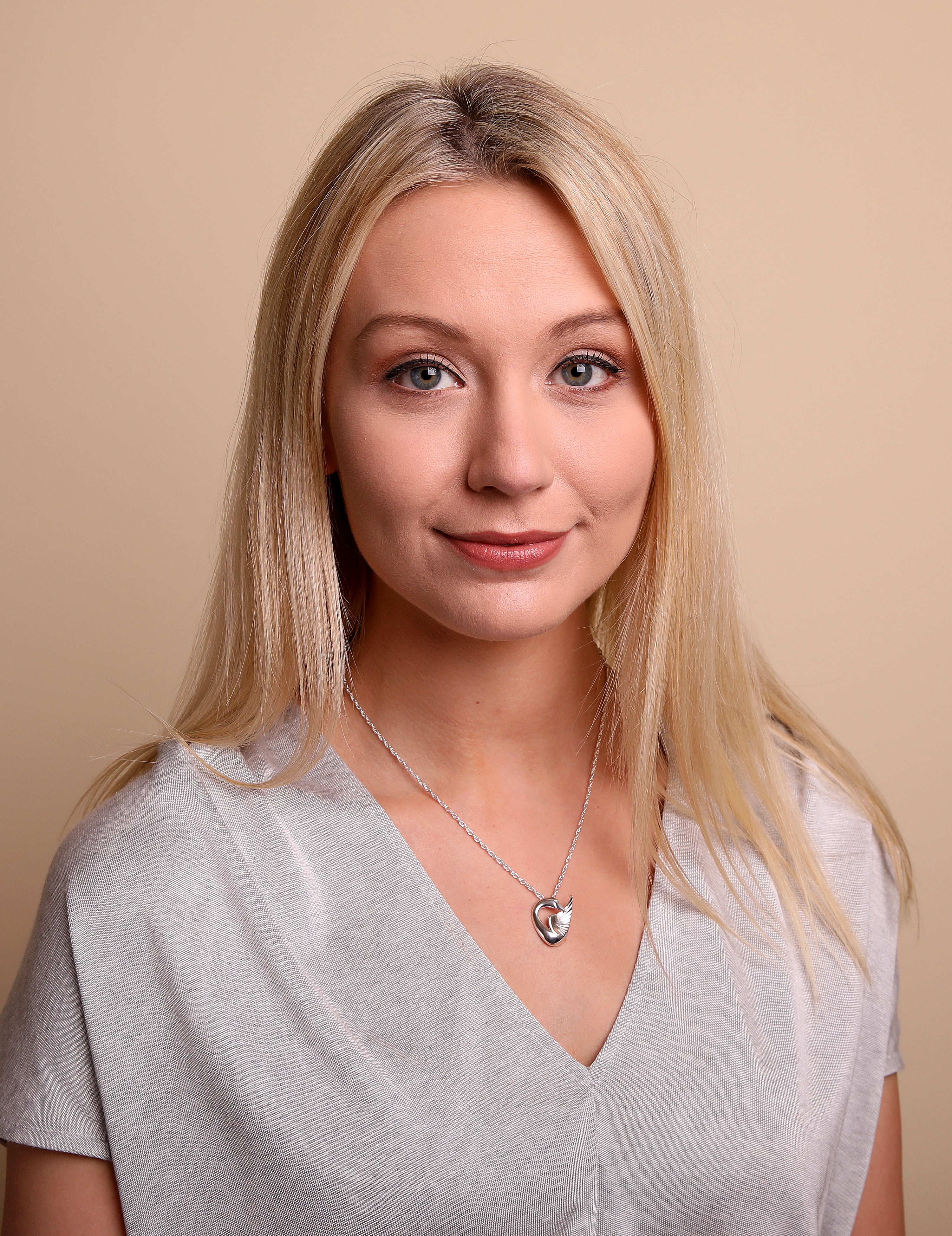 A woman wearing a grey top is modelling a silver necklace