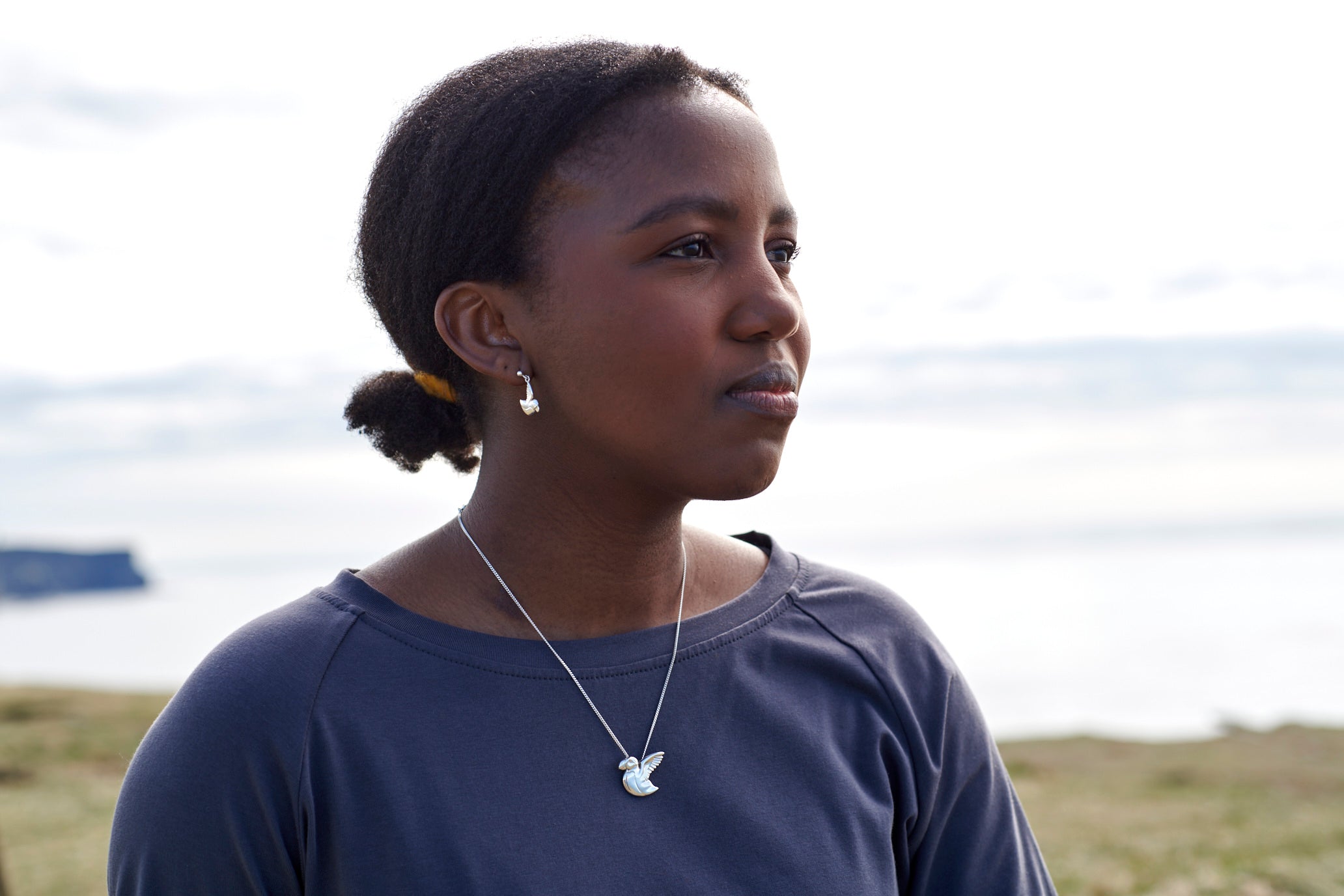 Close up of woman wearing silver puffin  earring and necklace
