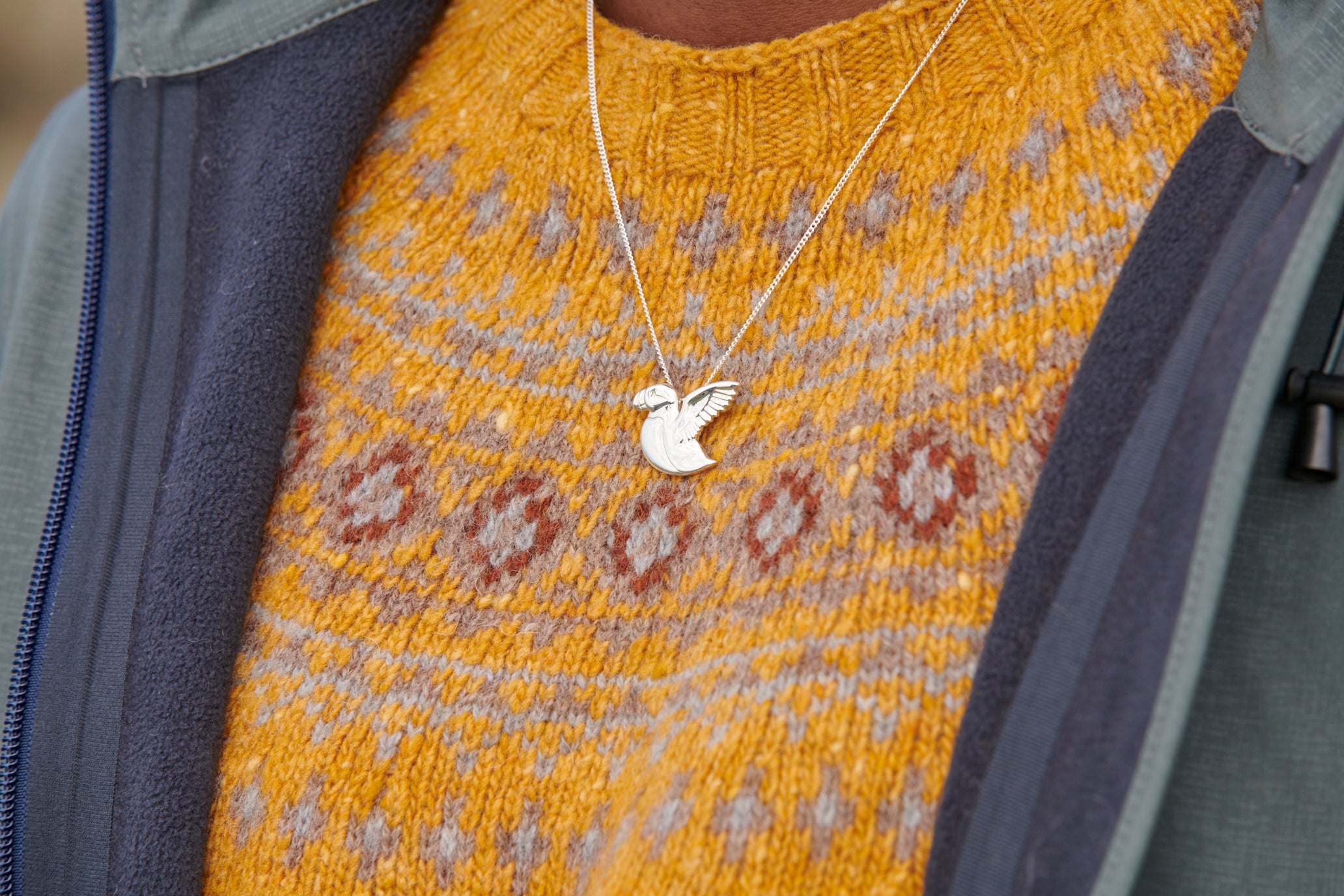 Close up of a woman wearing a silver puffin necklace