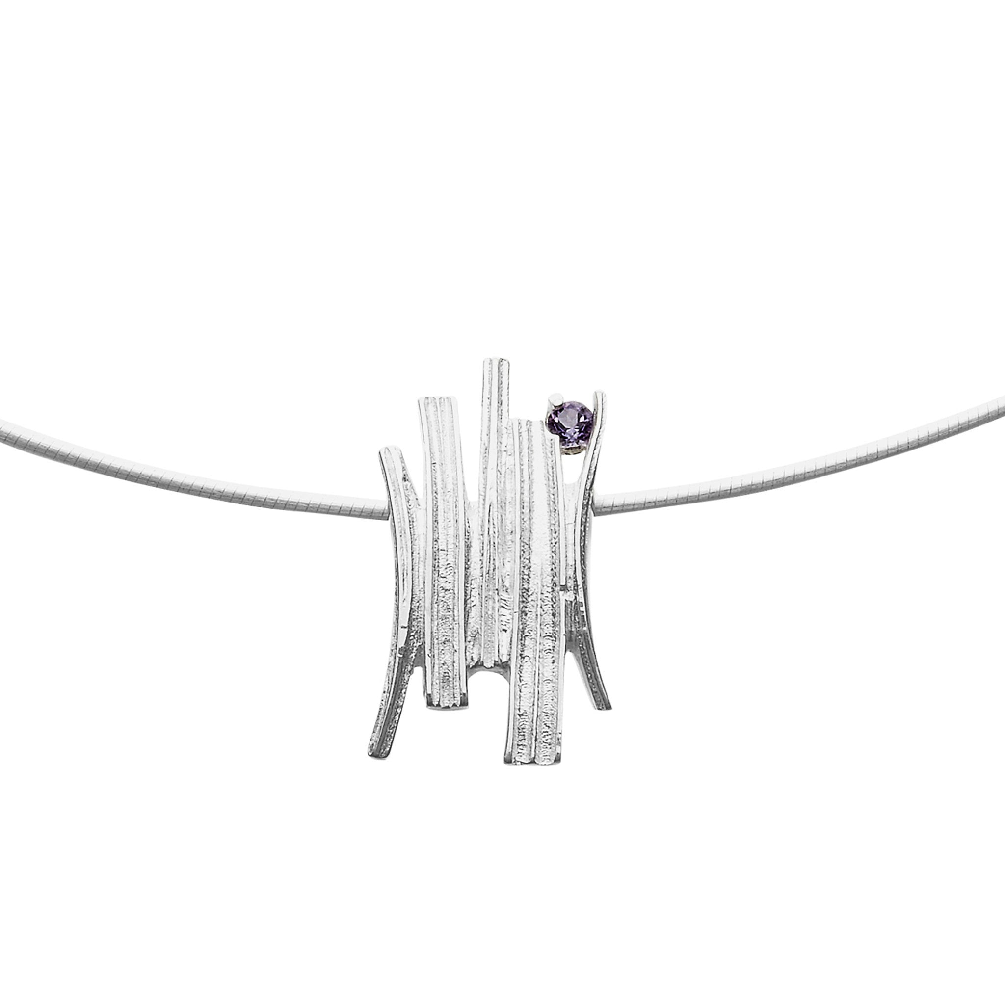 A silver necklace with a pendant that has a grass like design finished with a purple gem stone